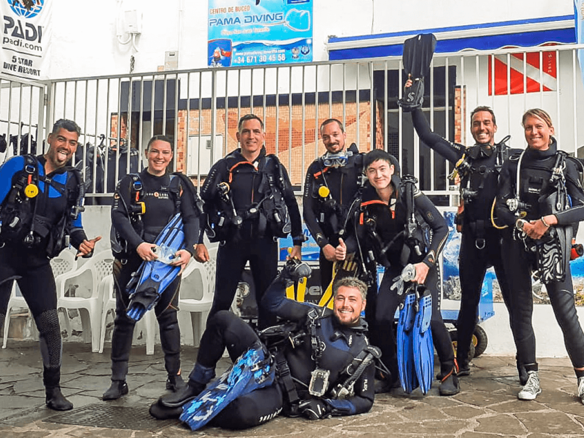 MUI team members and their diving instructors pose in scuba gear before a scuba diving lesson.